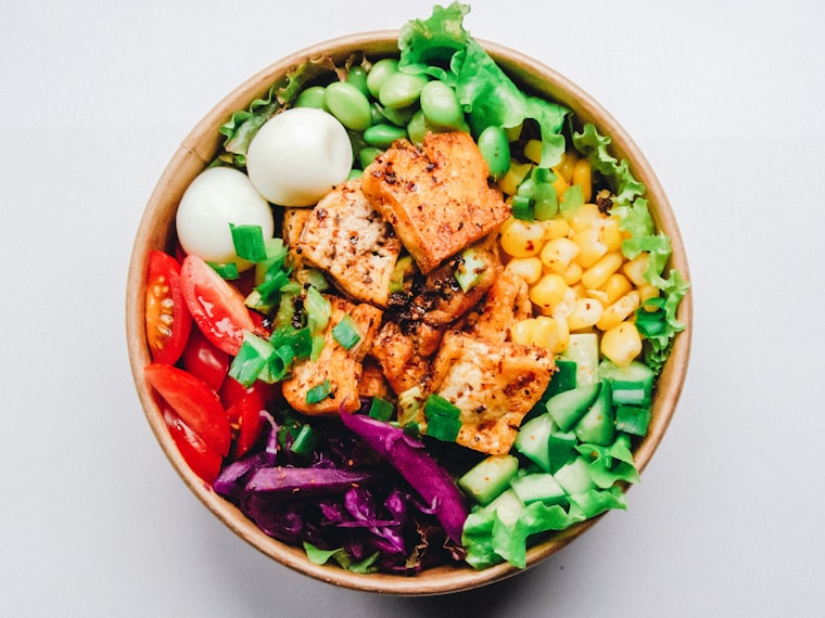 Photo of a chicken bowl with corn, eggs and greens